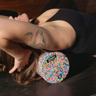 Woman using Xpeed medium density foam roller during a yog class