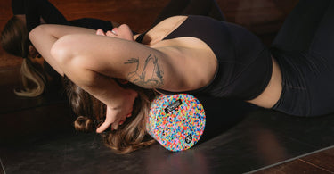 Woman using Xpeed medium density foam roller during a yog class