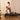 Woman exercising on a Pilates reformer machine in a home setting.