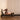 Woman using a Pilates reformer machine in a room with beige walls and wooden floor.