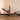 Woman exercising on a Pilates reformer machine in a room with beige curtains.