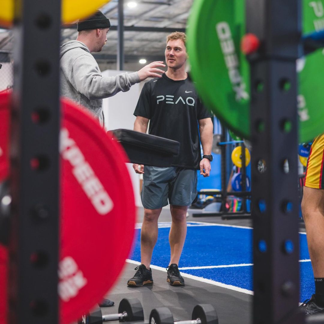 Coach talking to an athlete in the Xpeed Alpha Half Rack at PEAQ Performance Adelaide